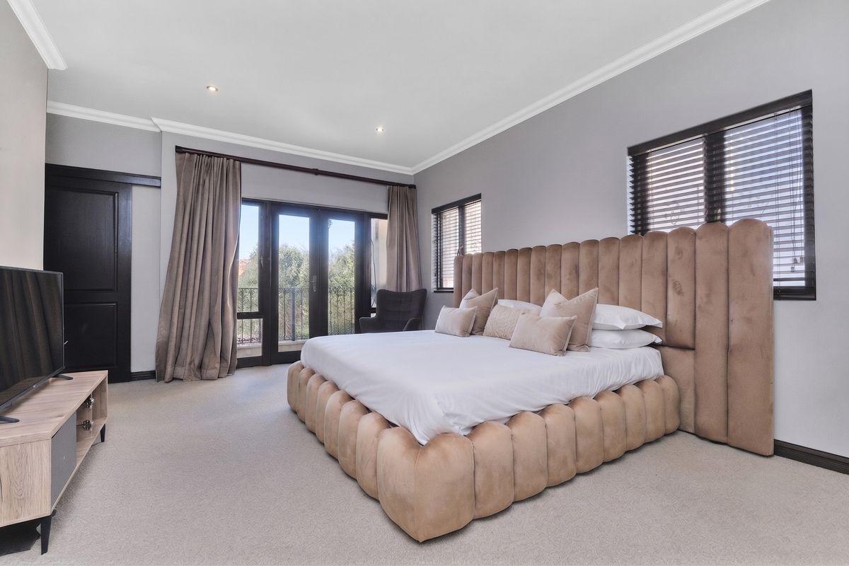 Spacious bedroom featuring neutral carpeting, crown molding, recessed lighting, and direct access to a private balcony through glass sliding doors.