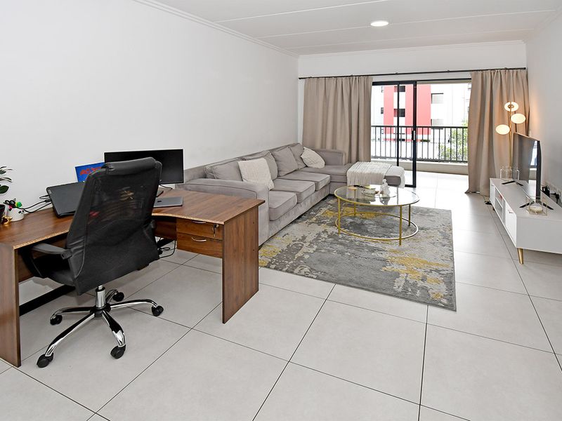 Spacious living room featuring large format floor tiles, recessed lighting, and a sliding glass door providing direct access to the balcony.