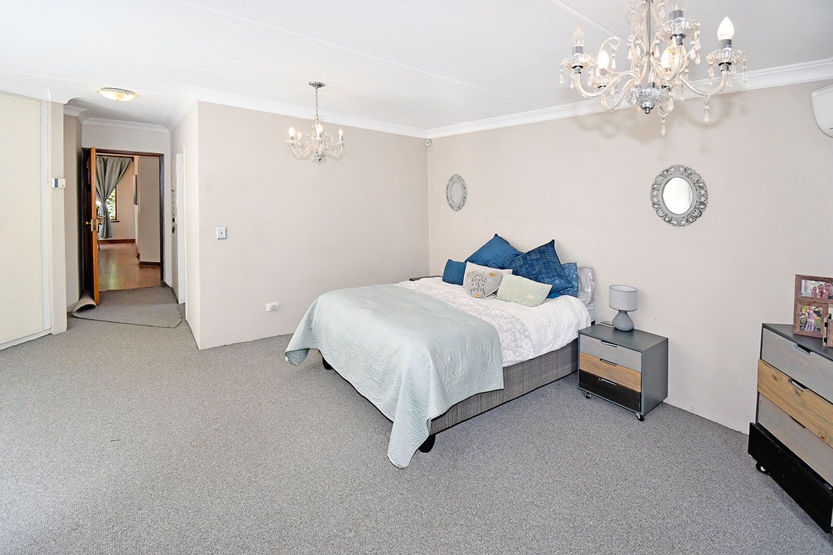Spacious bedroom featuring neutral walls, carpeted flooring, coved ceilings, and a built-in cupboard, offering a comfortable and functional living space.