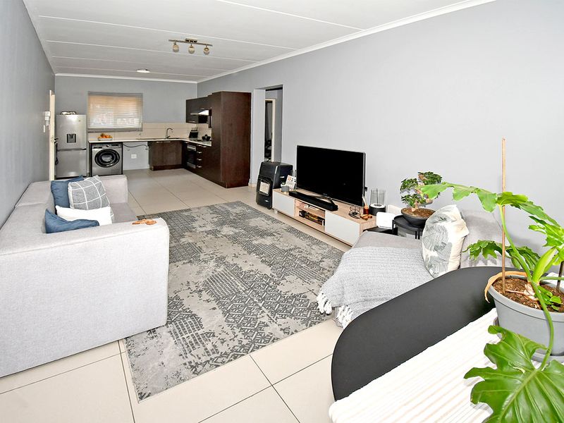 Open-plan living area featuring tiled flooring and a functional kitchen with built-in cabinetry, integrated oven, and extractor fan.