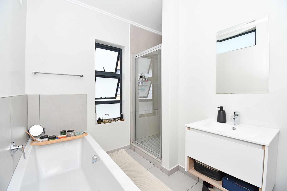 Modern bathroom featuring a white bathtub, a glass-enclosed shower, and a contemporary wall-mounted vanity with a basin.