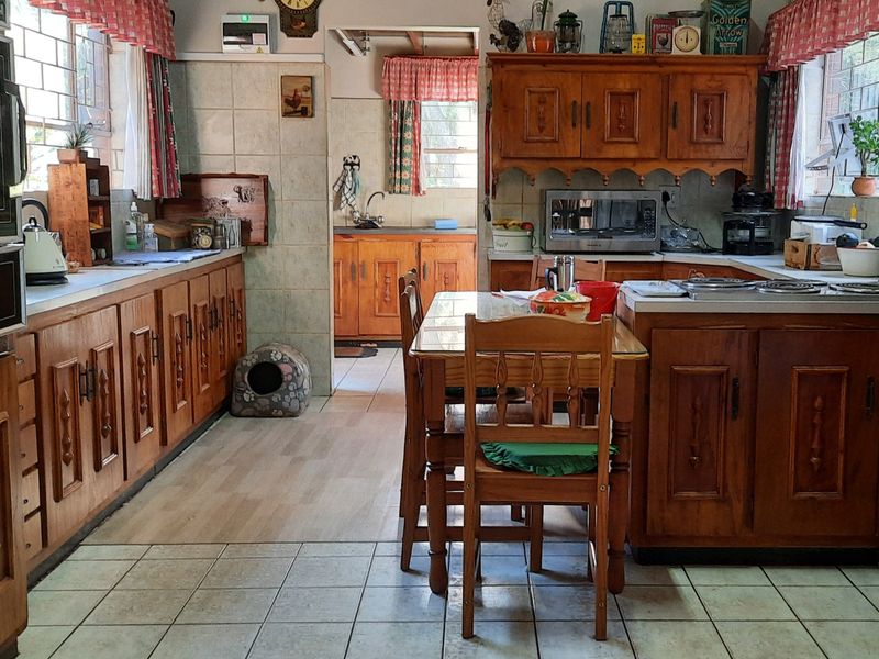 A spacious kitchen featuring traditional wooden cabinetry, built-in oven, and a functional layout with an adjoining scullery area.
