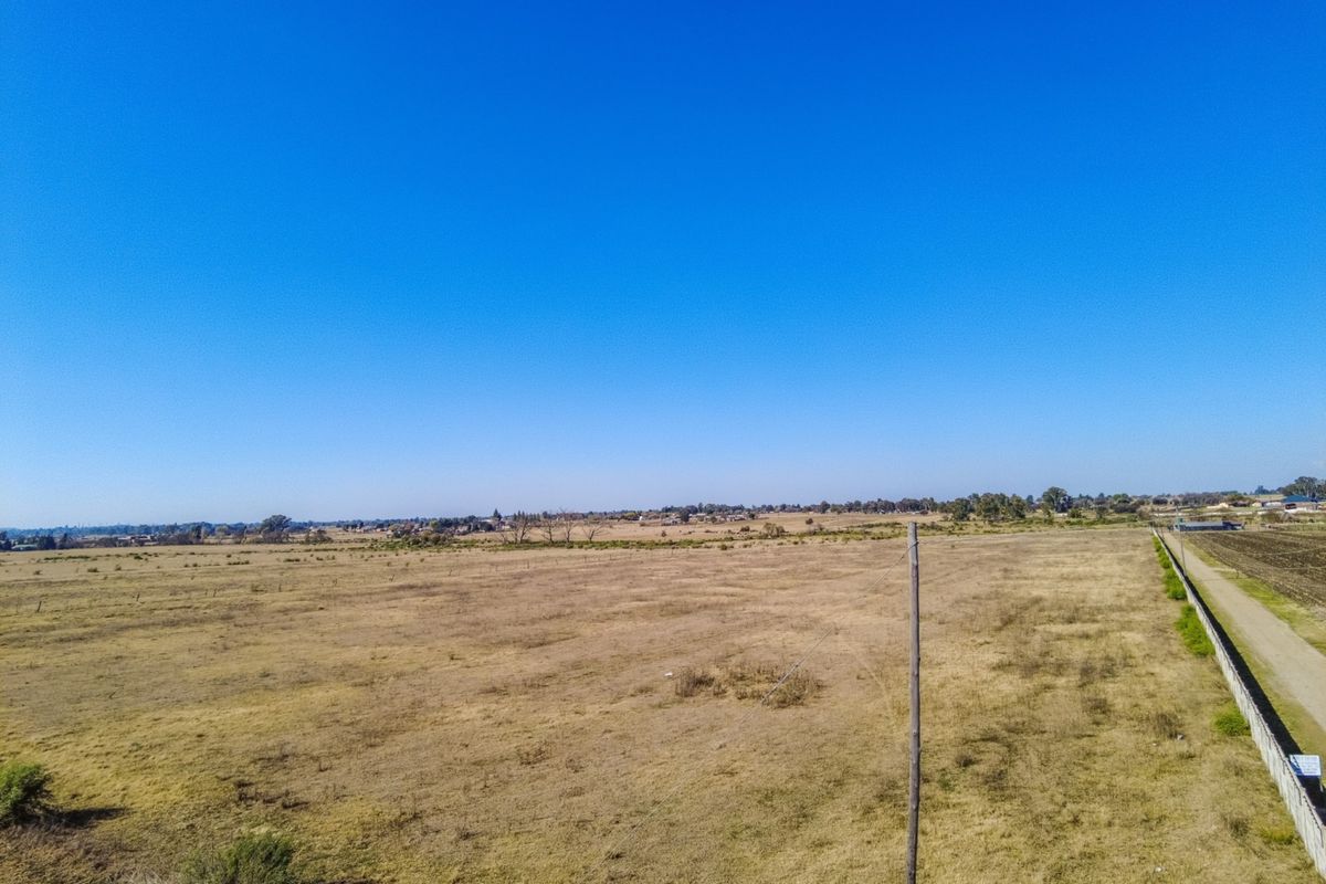 An expansive aerial view of the open land and surrounding landscape, showcasing the vast potential of the small holding property.