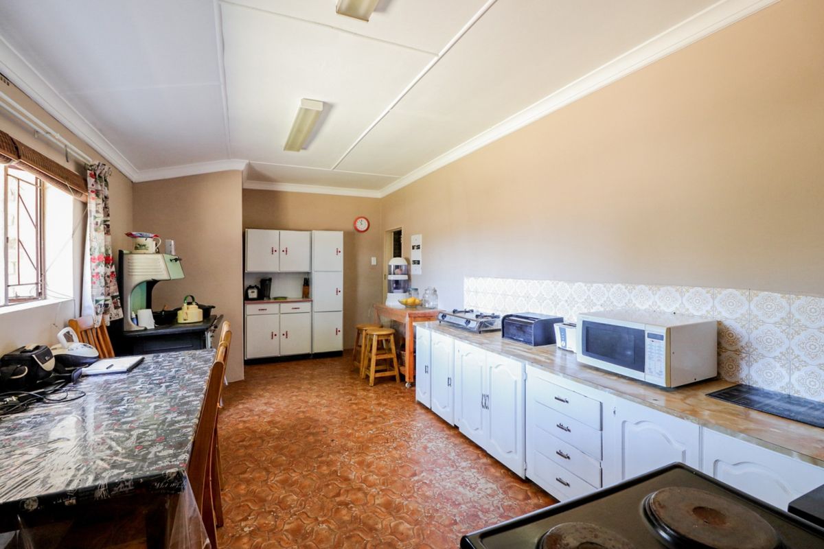 A functional kitchen area featuring white cabinetry, tiled backsplash, and durable flooring, offering a practical layout for daily meal preparation.