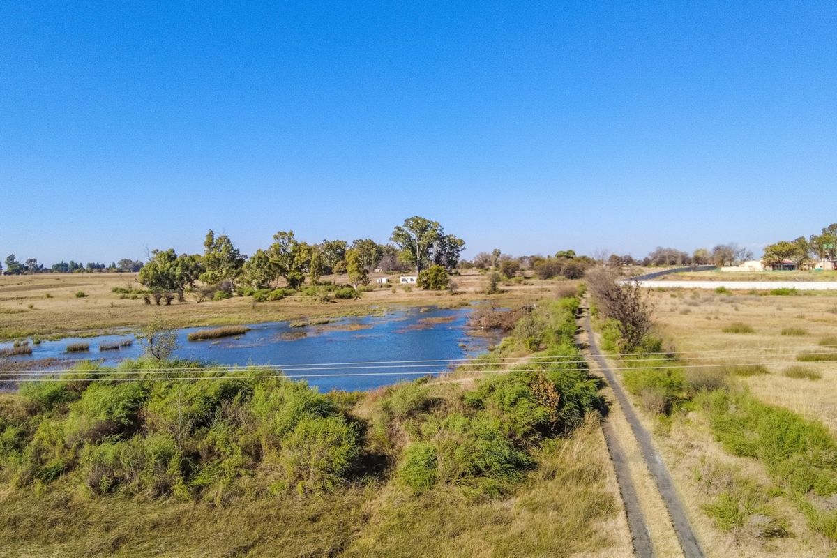Aerial view of the small holding featuring a natural dam, surrounding open veld, and a gravel access track.