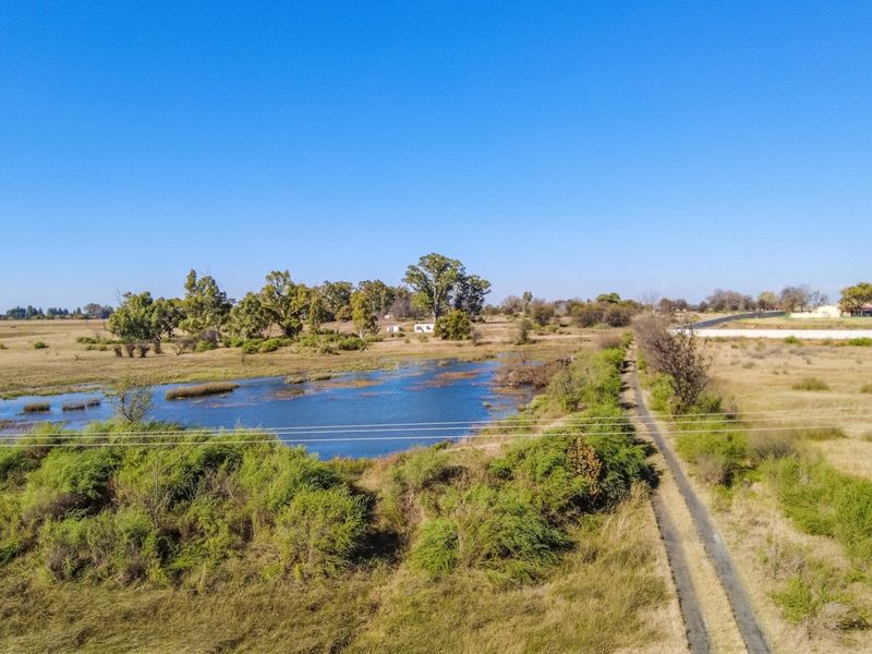 Aerial view of the small holding featuring a natural dam, surrounding open veld, and a gravel access track.