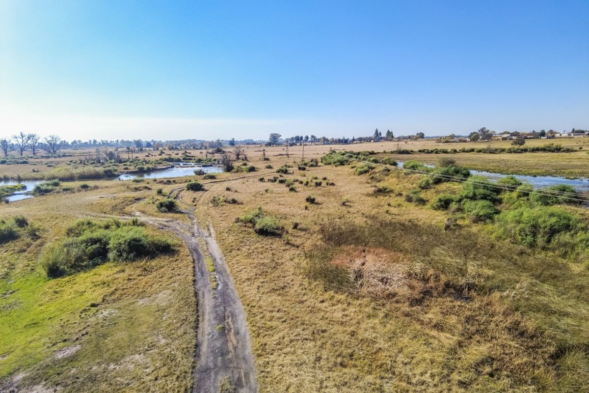 Aerial view of the small holding property featuring expansive open land, a dirt access road, and natural river frontage.