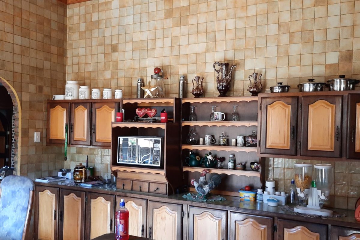 A traditional kitchen featuring extensive wall tiling and wooden cabinetry with integrated shelving and built-in microwave space.