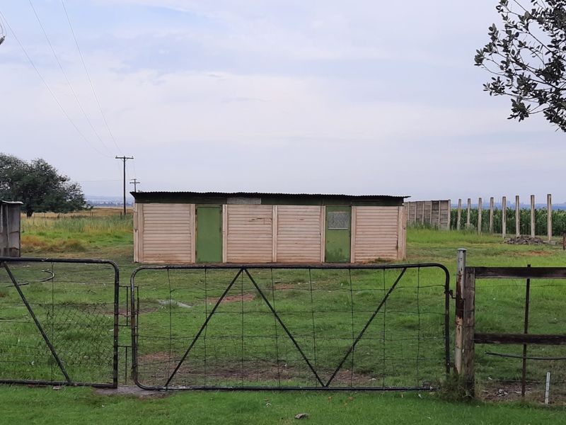 A detached utility outbuilding with timber cladding and a corrugated metal roof, situated on a rural small holding property.