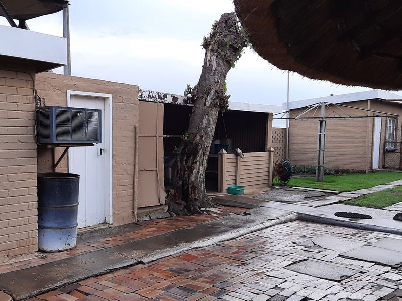 Rear exterior area featuring brick paving, a rotary clothesline, and a small outbuilding with an evaporative cooler unit.