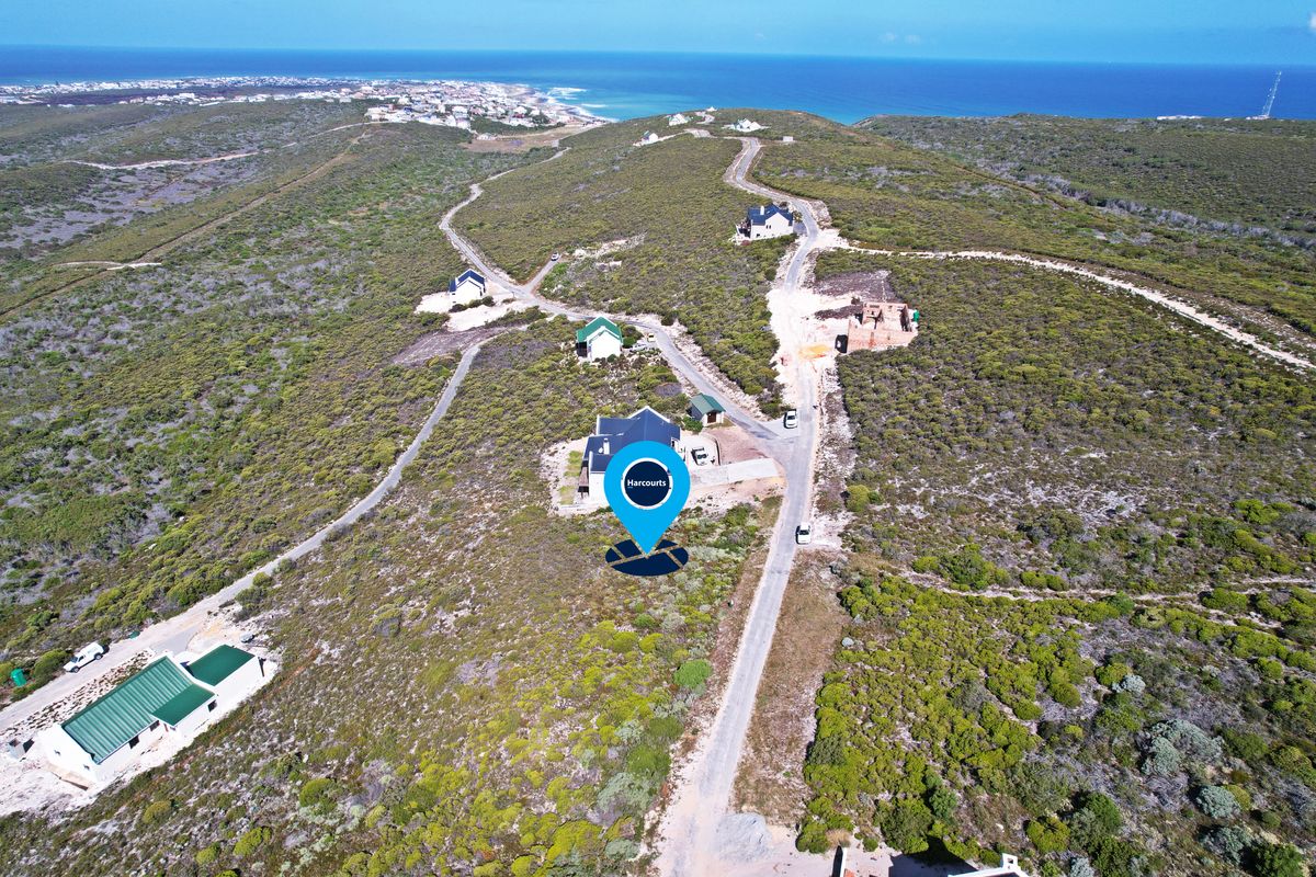 Aerial view of a vacant residential plot situated in a coastal landscape with established gravel road access and surrounding natural vegetation.