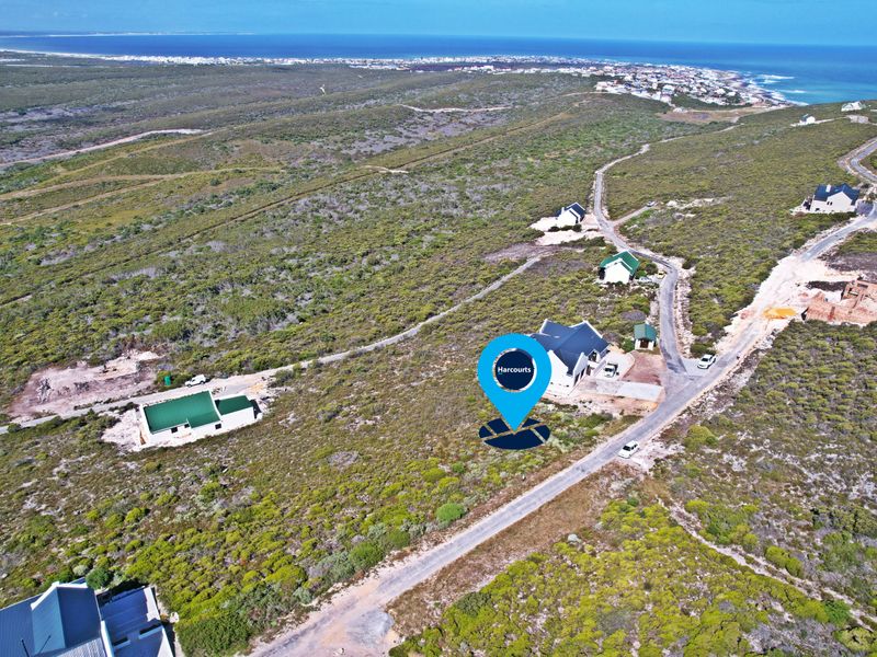 Aerial view of a residential land plot situated in a coastal estate with established access roads and surrounding natural vegetation.