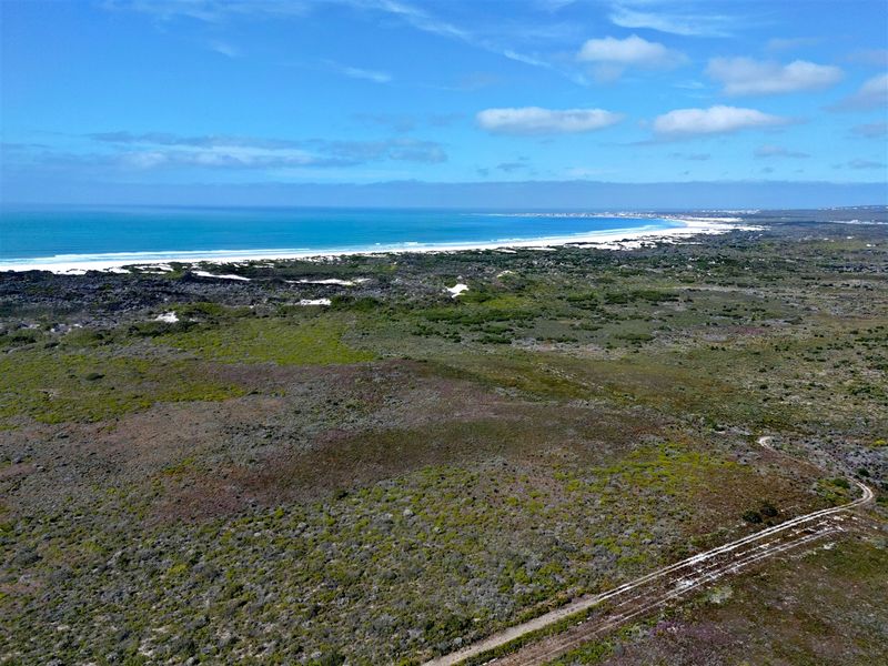 Aerial view of expansive vacant residential land featuring natural coastal vegetation and proximity to the ocean shoreline.