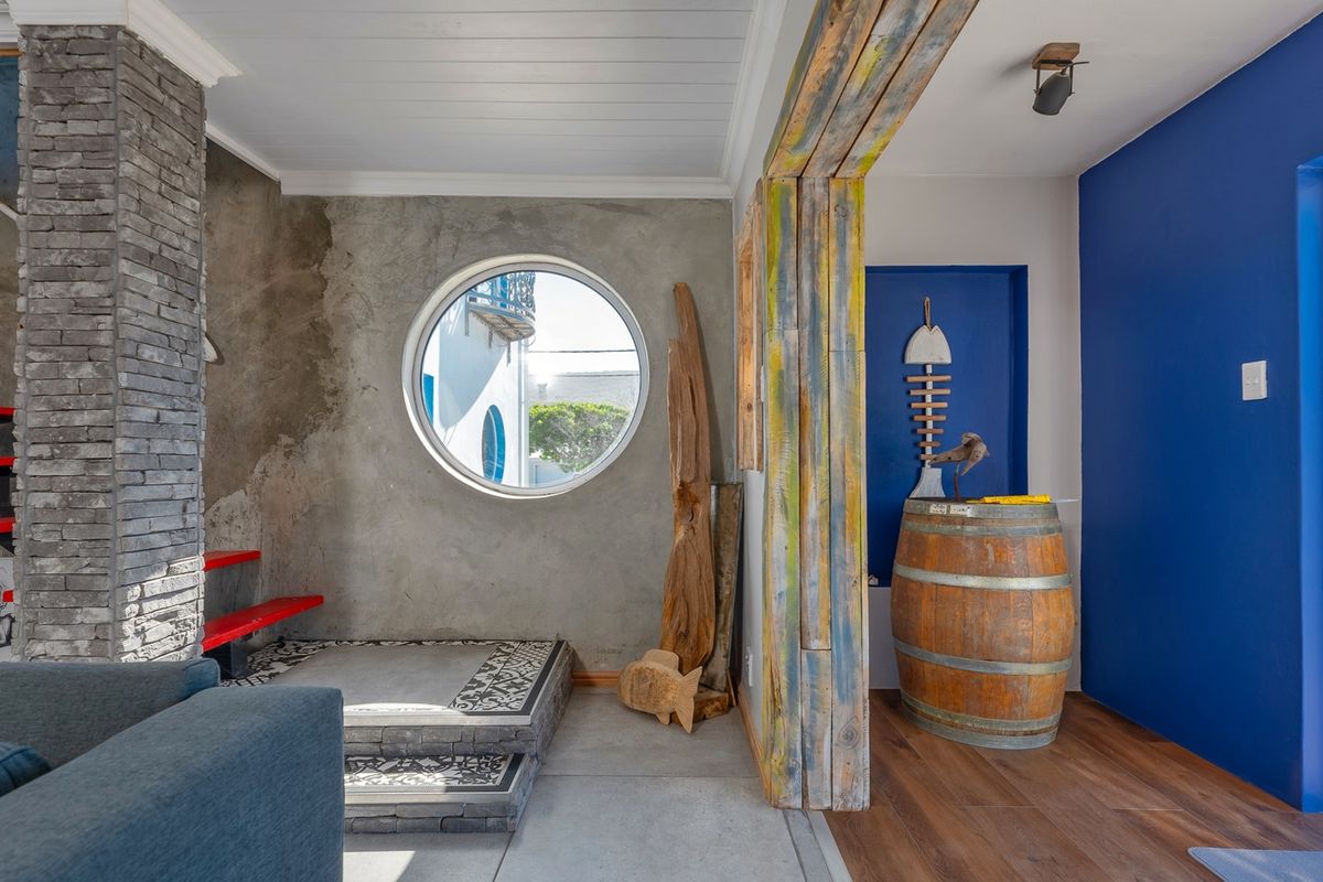 Living area featuring a unique circular window, stone-clad pillar, floating staircase, and direct access to the outdoors through a sliding glass door.