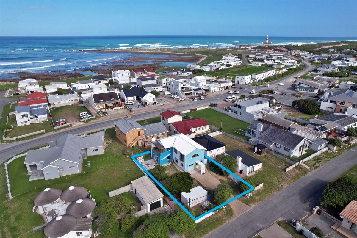 Aerial view of the coastal property highlighting the building footprint, surrounding garden, detached garage, and proximity to the ocean and local lighthouse.