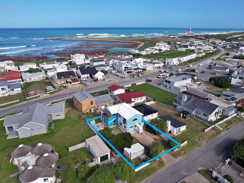 Aerial view of the coastal property highlighting the building footprint, surrounding garden, detached garage, and proximity to the ocean and local lighthouse.