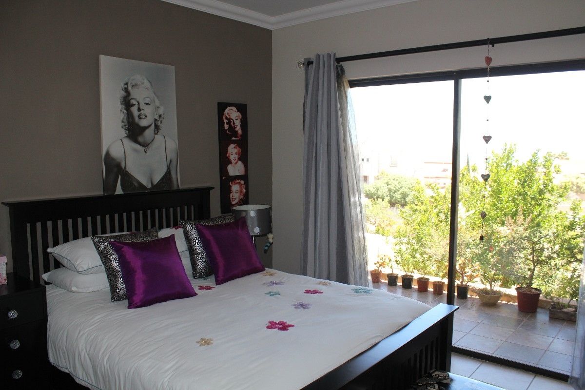 A well-maintained bedroom featuring a sliding glass door that opens onto a private balcony with garden views.