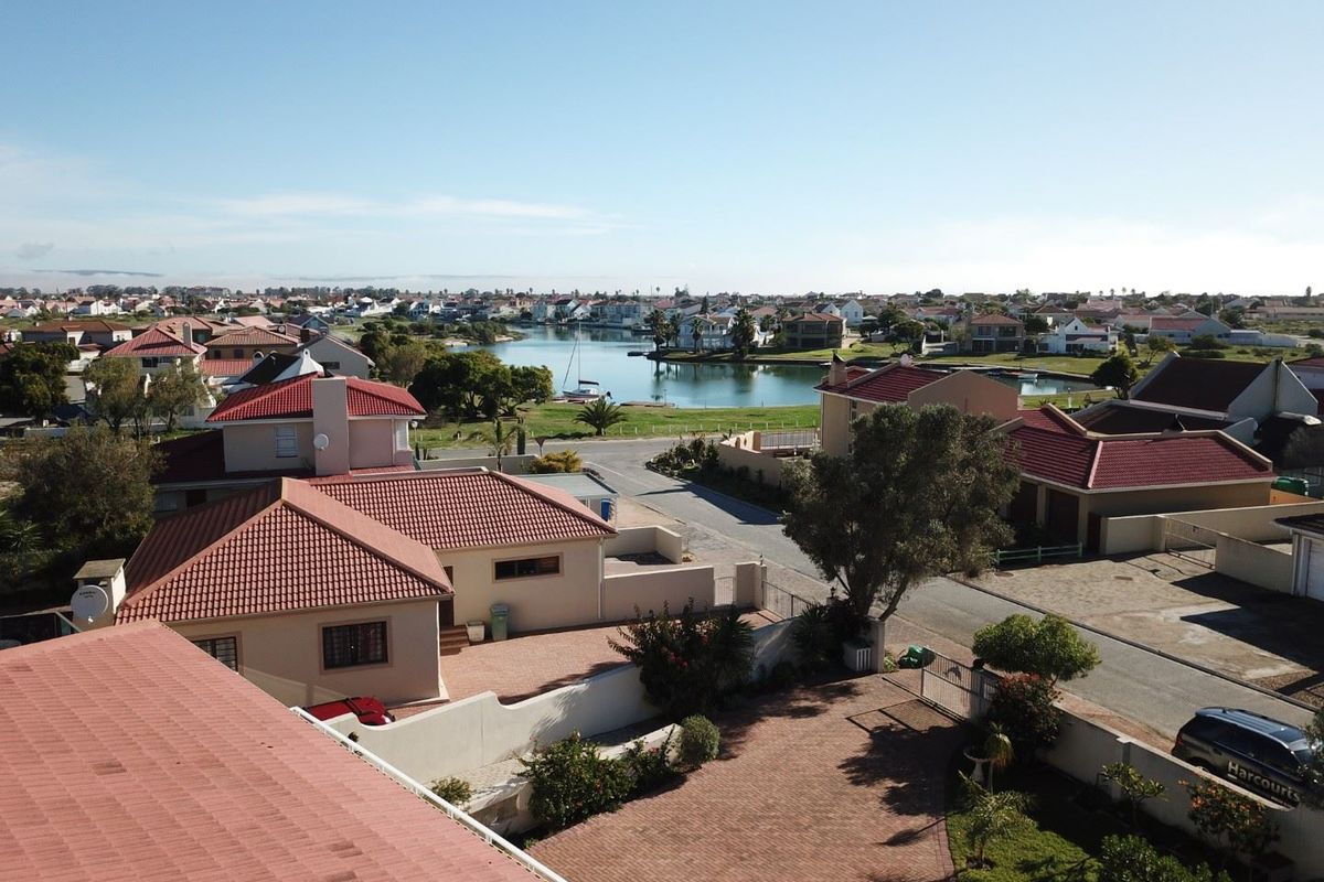 Aerial view of the residential estate featuring tiled roof homes, paved driveways, and a scenic outlook over the nearby lagoon and neighborhood.