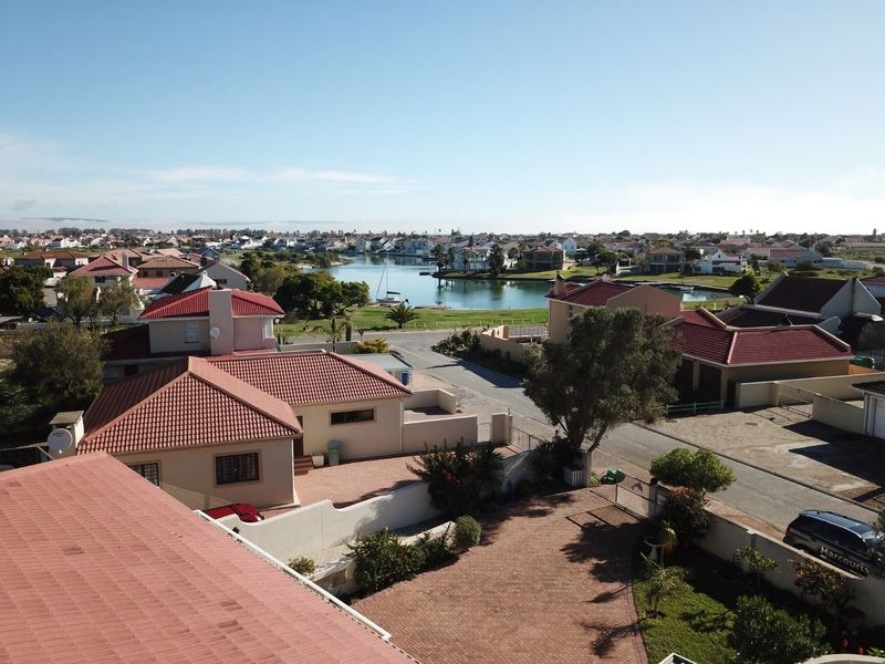 Aerial view of the residential estate featuring tiled roof homes, paved driveways, and a scenic outlook over the nearby lagoon and neighborhood.