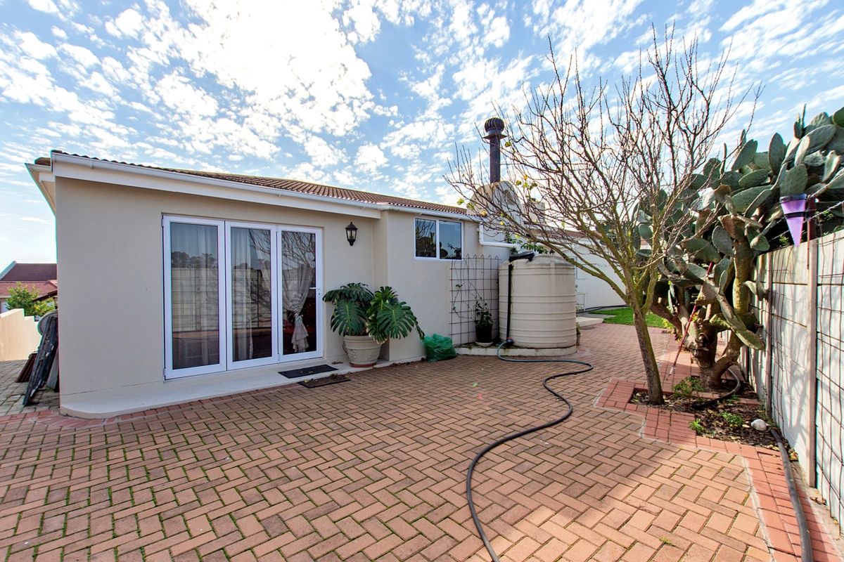 Rear exterior view featuring a brick paved patio area, water storage tank, and access to the home via sliding glass doors.