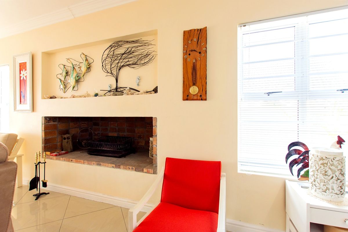 Living room featuring a built-in brick fireplace with an integrated wall niche above, tiled flooring, and natural light through venetian blinds.