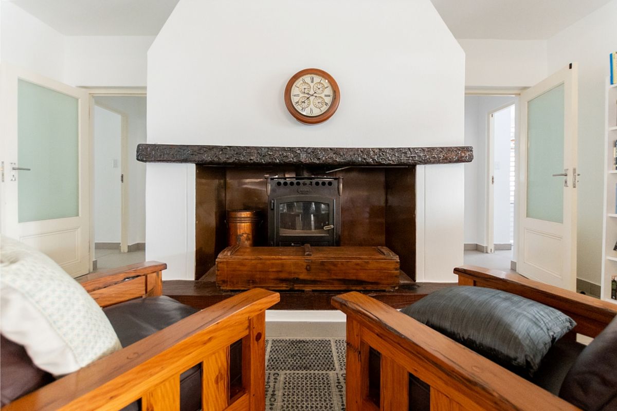 A cozy living room featuring a prominent wood-burning fireplace with a rustic timber mantelpiece, flanked by double internal doors.