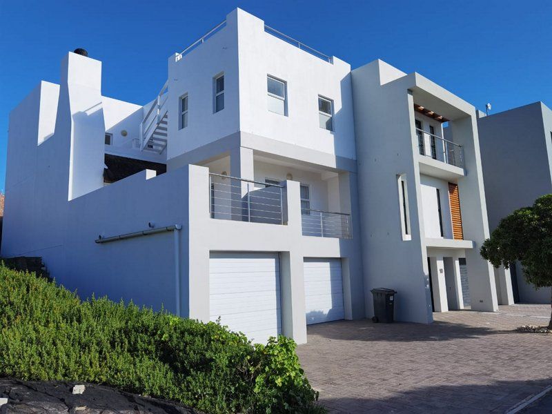 Modern multi-story residential property featuring a double garage, paved driveway, and upper-level balconies with stainless steel railings.