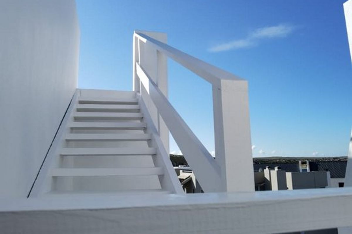 An external staircase providing access to an upper level, featuring a white painted finish and safety railing.