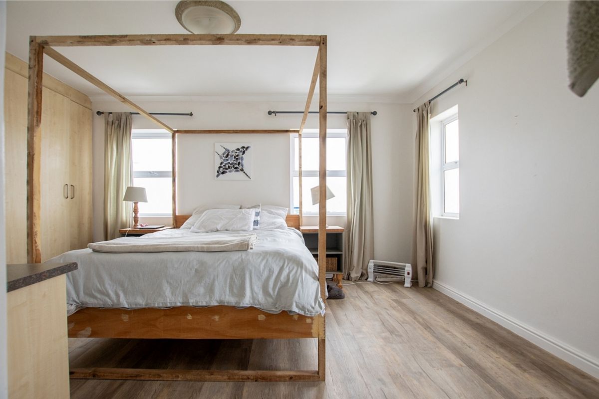 A bright bedroom featuring laminate flooring, built-in cupboards, and large windows allowing for ample natural light.