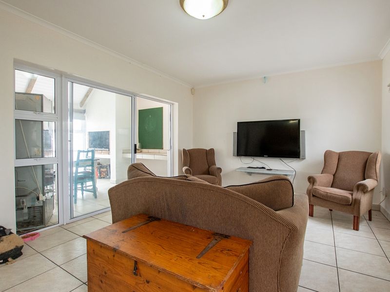 A bright living room featuring tiled flooring and large sliding glass doors that provide access to an adjacent patio area.