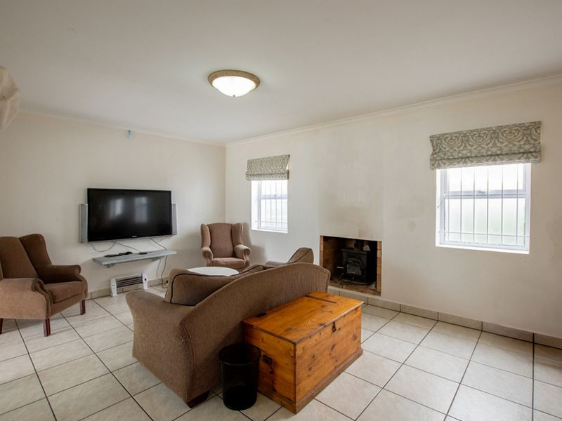 A living room featuring tiled flooring, a built-in fireplace, and windows fitted with security bars.