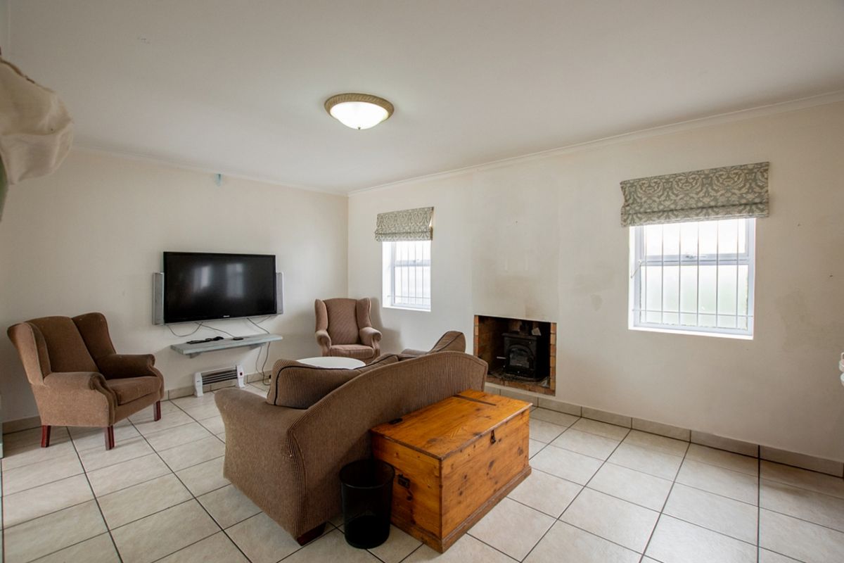 A living room featuring tiled flooring, a built-in fireplace, and windows fitted with security bars.