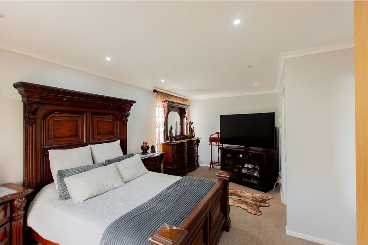 A spacious bedroom featuring neutral wall tones, recessed downlighting, and carpeted flooring, providing a comfortable and well-maintained living space.