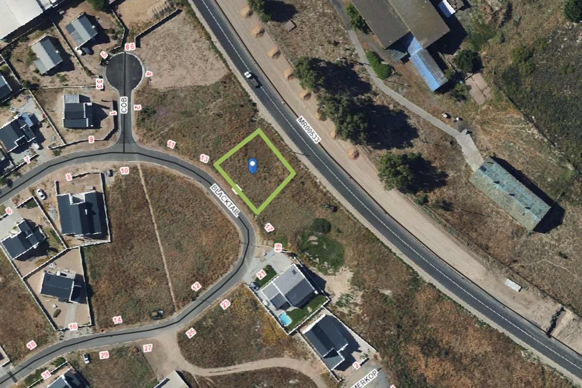 Aerial view of a vacant residential plot situated in a developed neighborhood with direct road access.