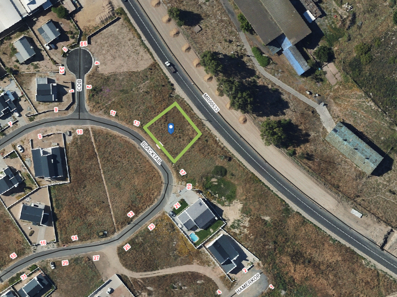 Aerial view of a vacant residential plot situated in a developed neighborhood with direct road access.
