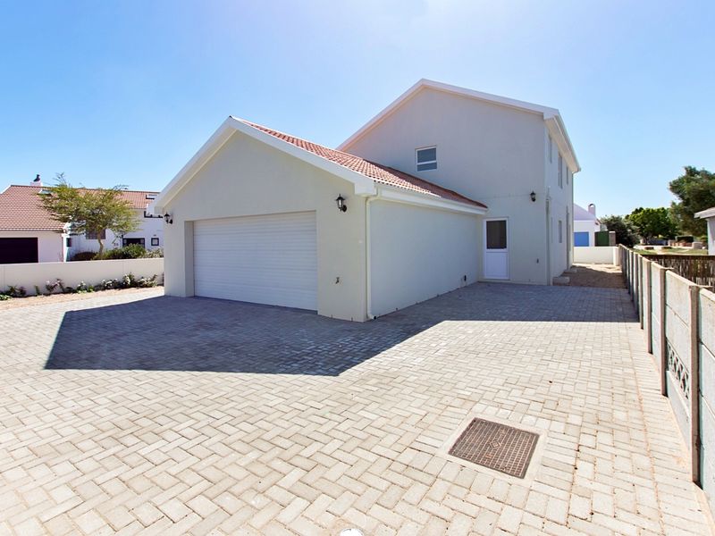 Front view of a residential property featuring a paved driveway, double garage, and well-maintained exterior walls under a clear sky.