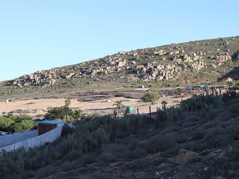 A wide-angle view of the vacant residential land, showcasing the natural landscape, rocky hillside terrain, and existing perimeter fencing.