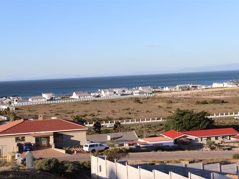 A wide-angle view of the coastal residential area, showcasing the surrounding landscape, neighborhood layout, and proximity to the ocean.