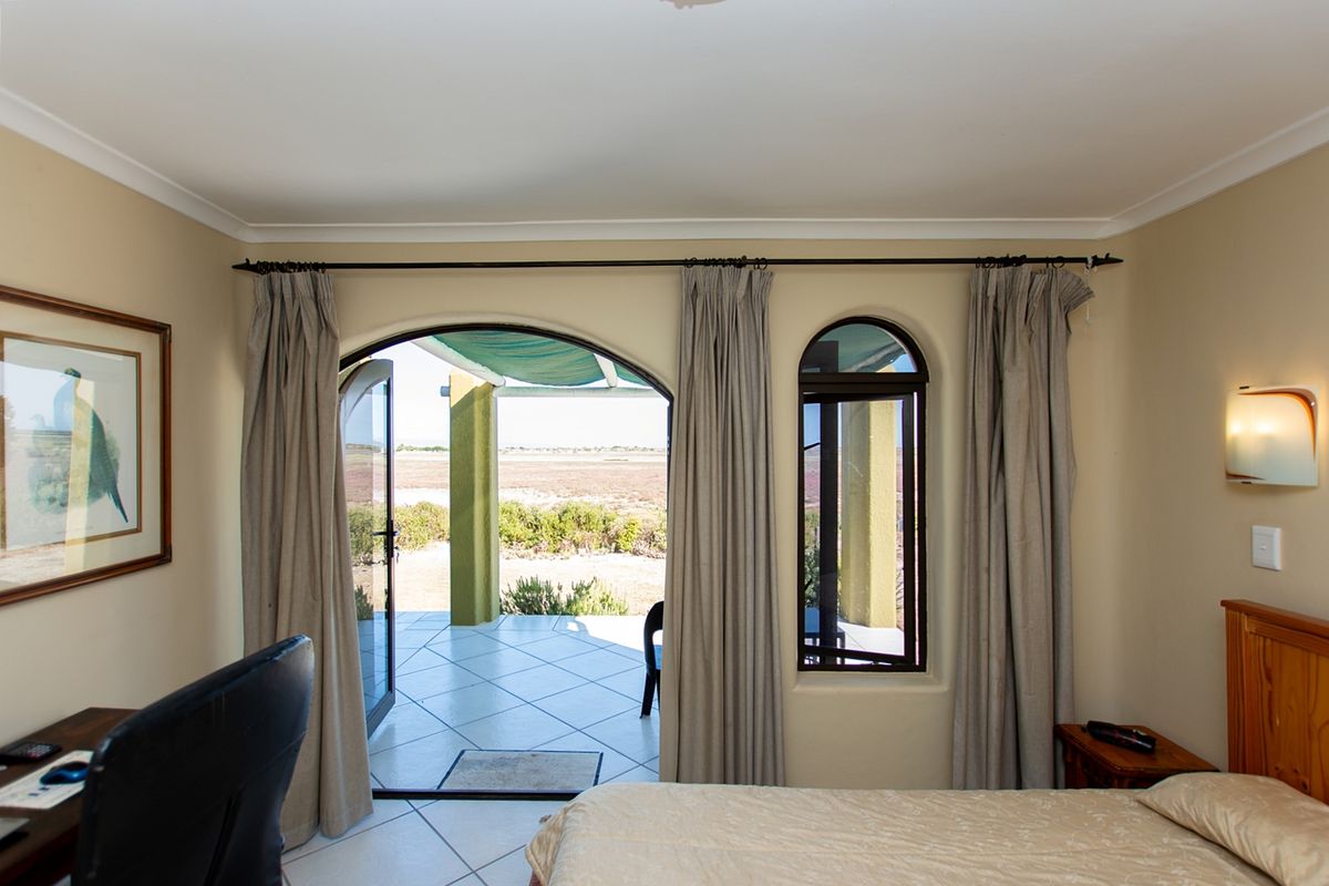 A bedroom featuring arched glass doors leading to a patio, neutral wall tones, and tiled flooring with direct access to the outdoor area.