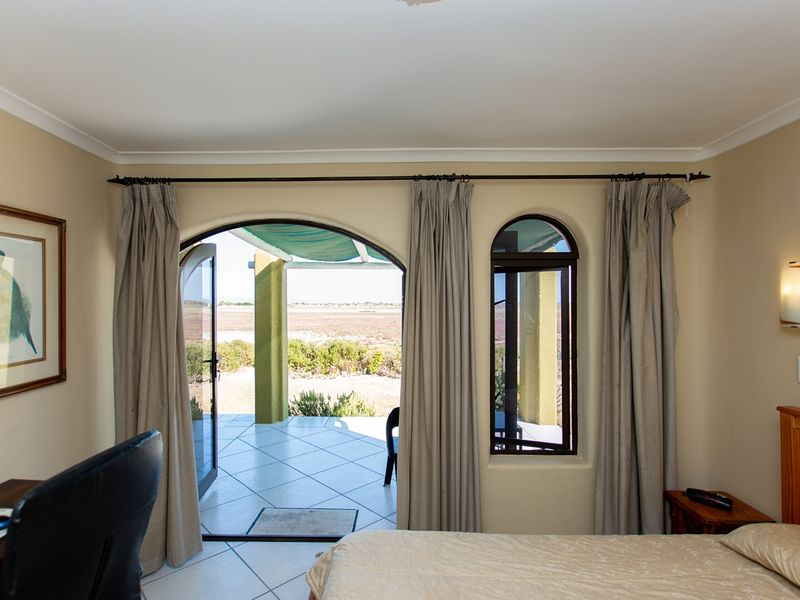 A bedroom featuring arched glass doors leading to a patio, neutral wall tones, and tiled flooring with direct access to the outdoor area.