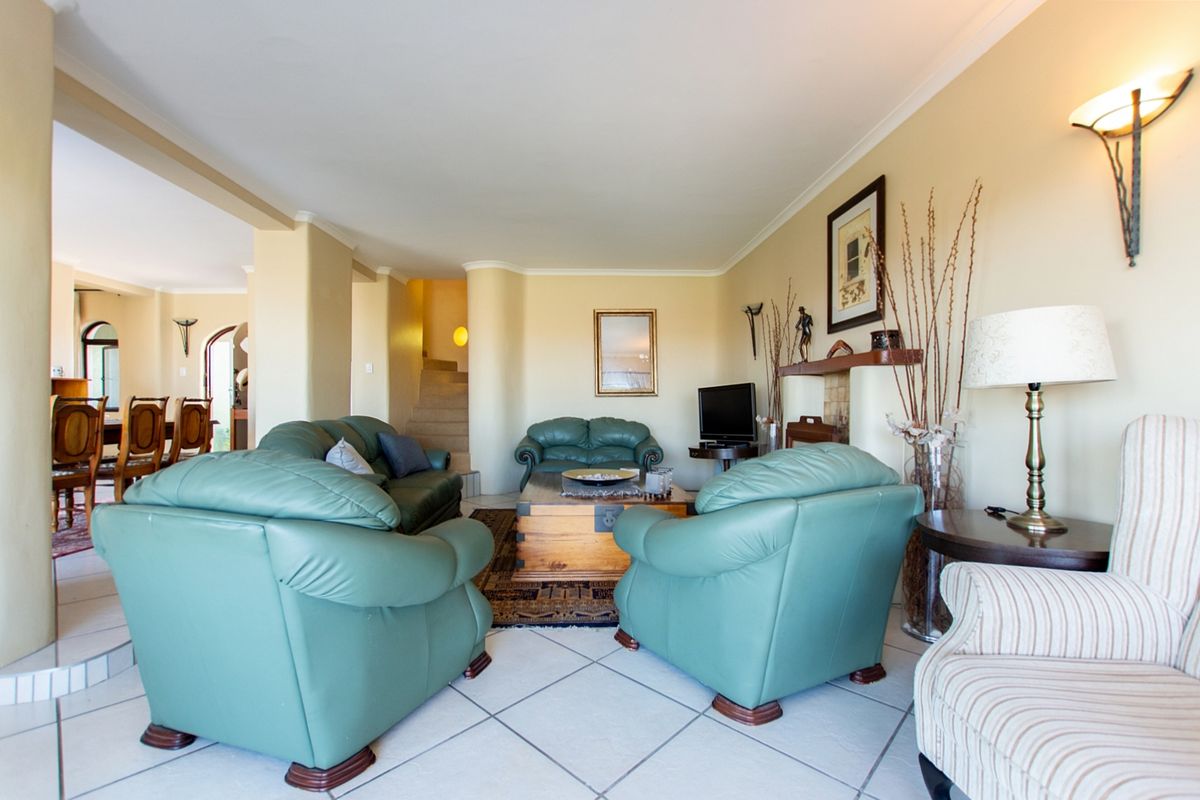 Spacious living room featuring tiled flooring, a fireplace, and wall sconce lighting, with an open-plan flow leading to the dining area.