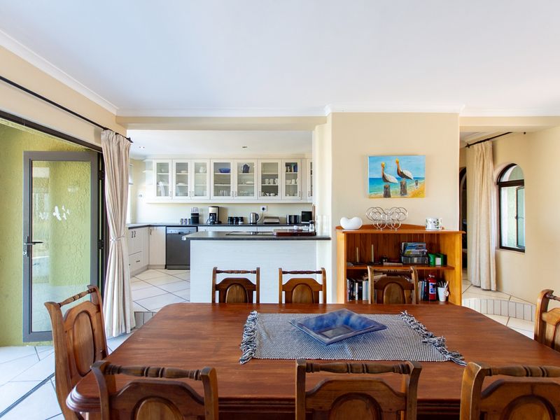 Open-plan dining and kitchen area featuring tiled flooring, ample cabinetry, and a sliding glass door leading to an outdoor space.
