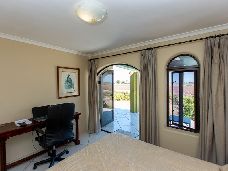 Bedroom featuring tiled flooring, an arched glass door leading to a patio, and an arched window with views of the surrounding landscape.