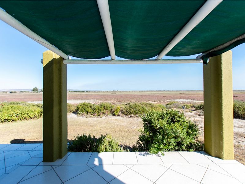 A covered patio area featuring tiled flooring and a retractable awning, offering expansive views of the surrounding natural landscape.