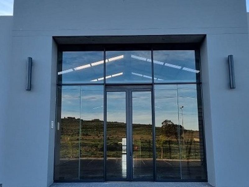 Modern retail storefront featuring a large glass facade with double entry doors and sleek exterior wall lighting.