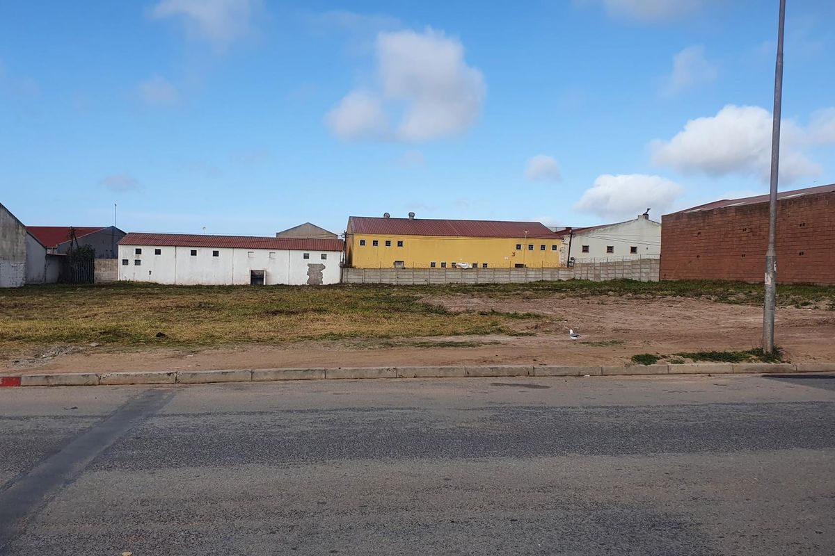 A vacant commercial land plot featuring a level surface, concrete curbing, and direct street access, situated in an established industrial area.