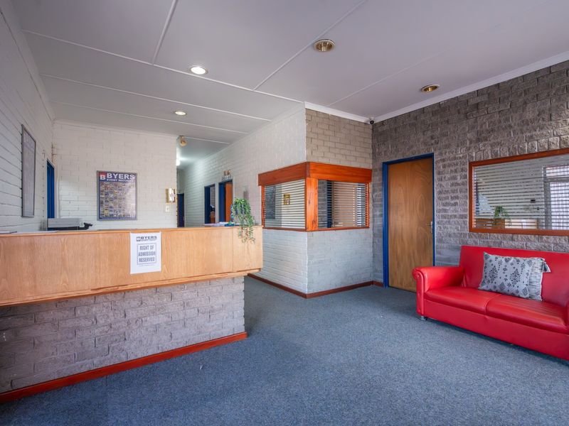 Commercial reception area featuring a built-in desk, exposed brick wall finishes, recessed lighting, and a functional layout suitable for a professional office environment.