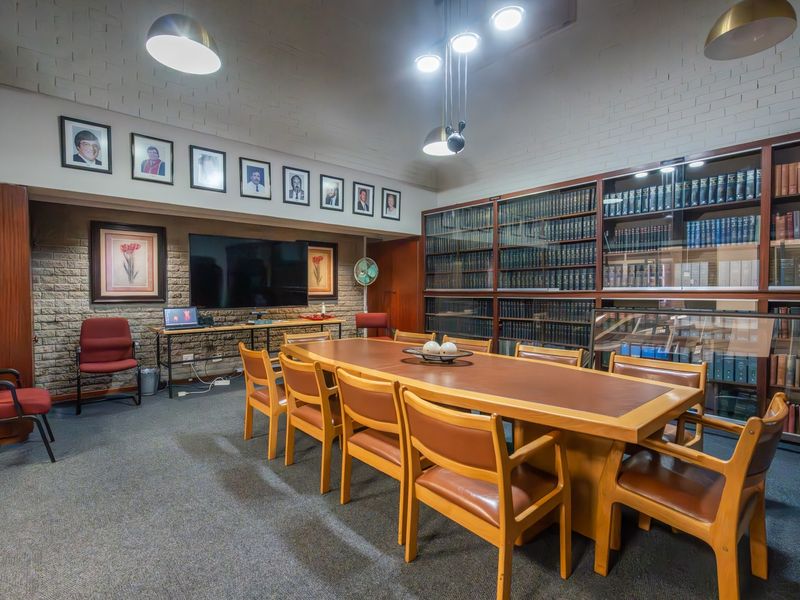 A professional boardroom or office space featuring extensive built-in library shelving, exposed brick walls, and integrated lighting fixtures.