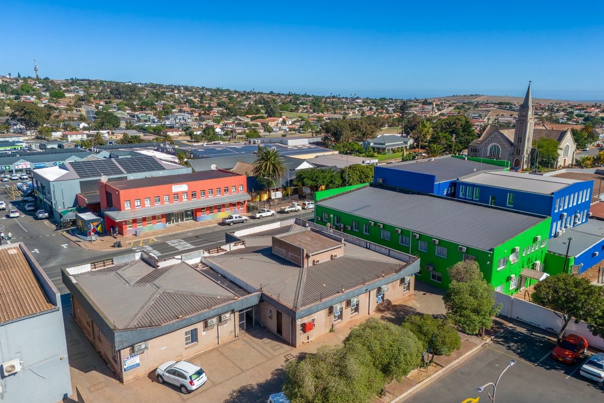 Aerial view of a commercial property complex featuring brick buildings, metal roofing, and paved parking areas within a suburban neighborhood setting.