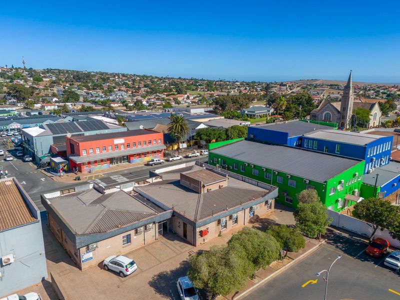 Aerial view of a commercial property complex featuring brick buildings, metal roofing, and paved parking areas within a suburban neighborhood setting.
